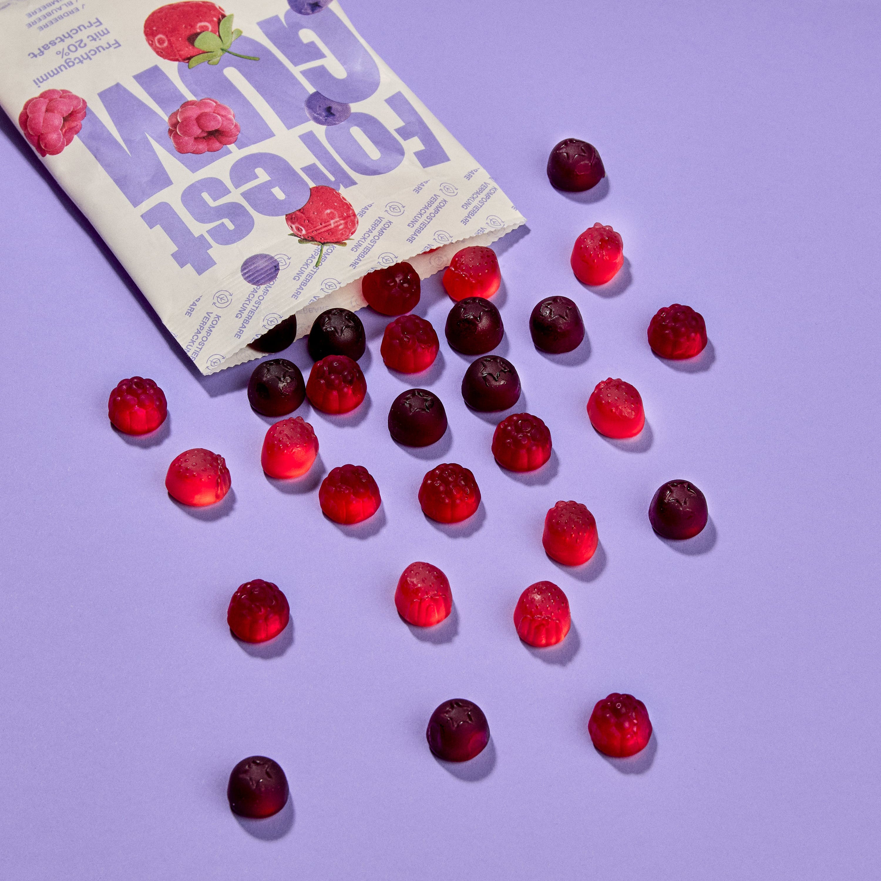 vegane Fruchtgummis in Form von Erdbeeren, Blaubeeren & Himbeeren, fallen aus kompostierbarer Verpackung.