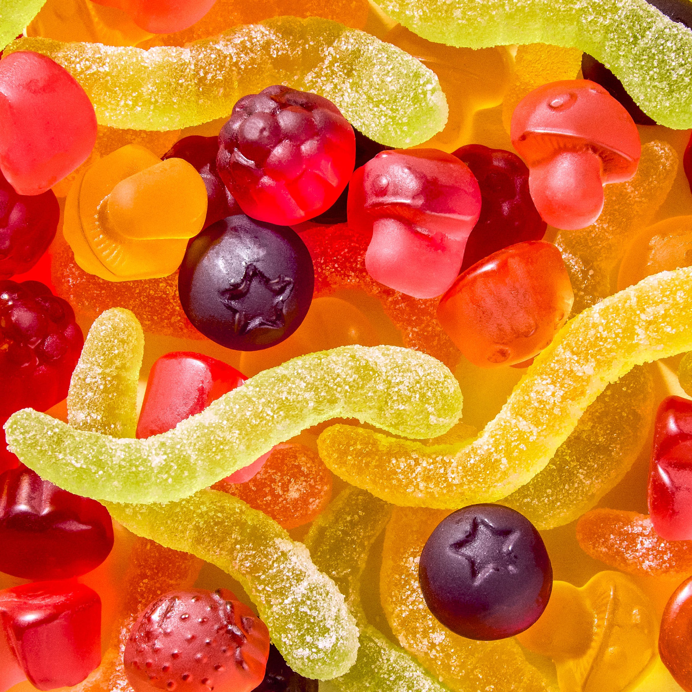 Nahaufnahme veganer Forest Gum Fruchtgummis Sour Wonder Worms, Magic Mushroom & Wild Berries, bunt gemischt auf einem Haufen.