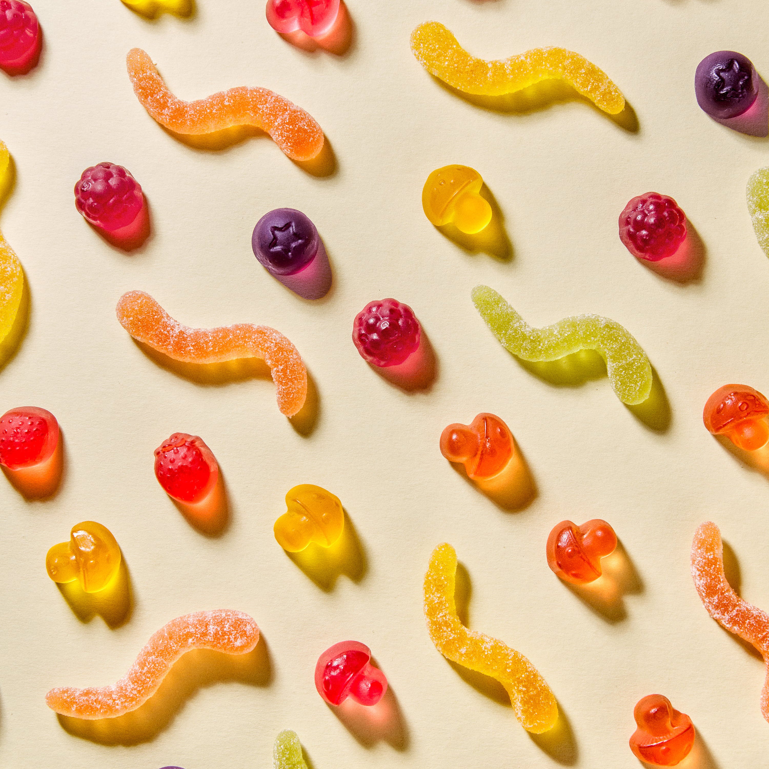 Vegane Forest Gum Fruchtgummis Sour Wonder Worms, Magic Mushroom & Wild Berries, diagonal auf weißem Boden angeordnet.