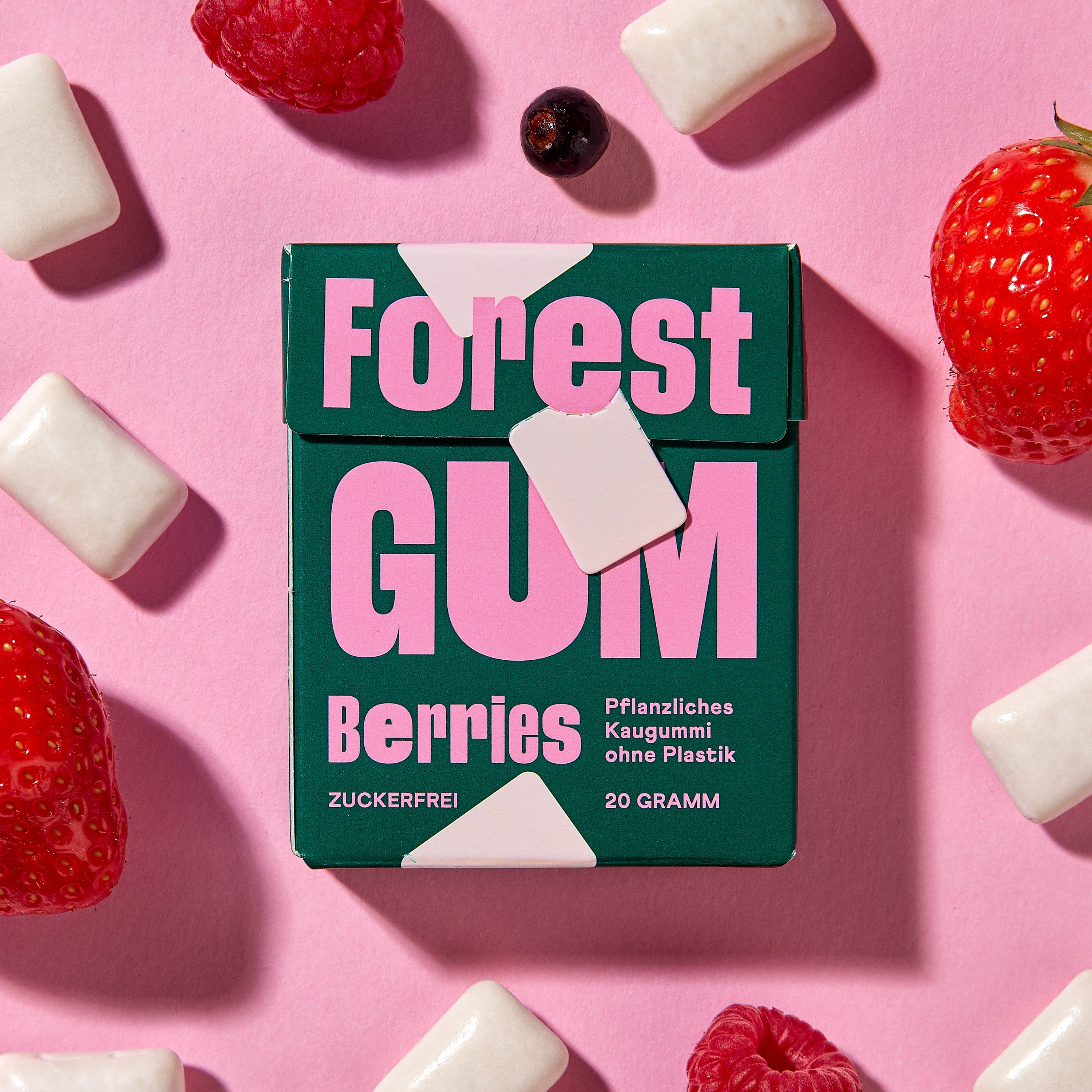 Forest Gum Berries Kaugummi-Packung, umgeben von Kaugummis, Erdbeeren, Himbeeren & Johannisbeeren.
